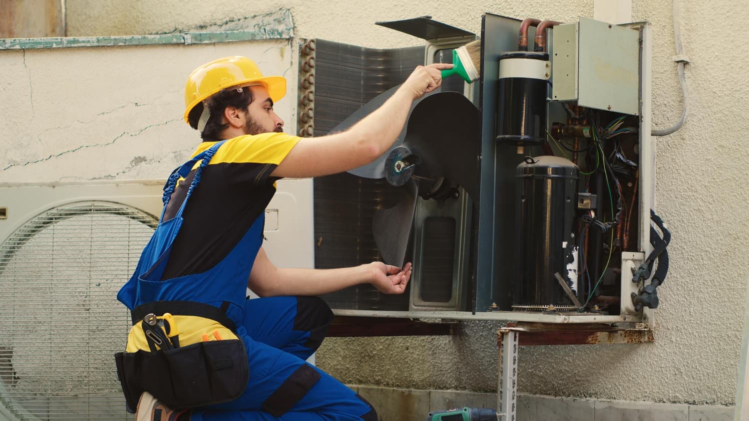 Technician working on an outdoor air-conditioning unit.