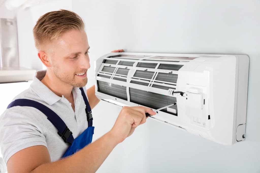 Technician inspecting an indoor air-conditioning unit.