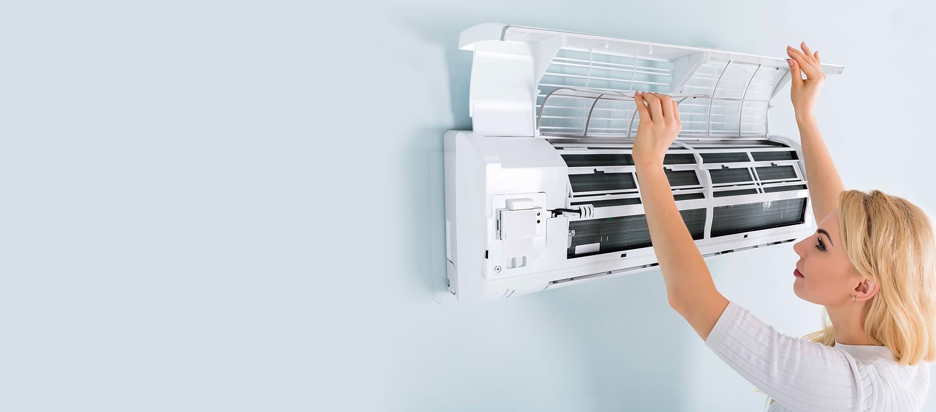 Technician servicing an open indoor air-conditioning unit.